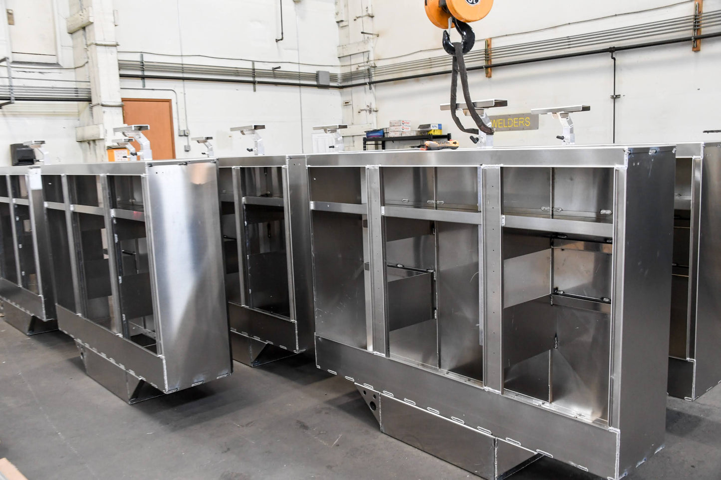 Row of industrial metal cabinets in a workshop setting with a crane in the background.