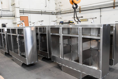 Row of industrial metal cabinets in a workshop setting with a crane in the background.
